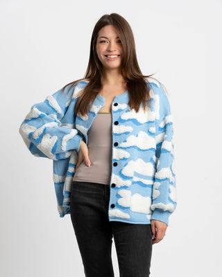 Woman wearing a blue and white cloud-patterned cardigan on a plain background