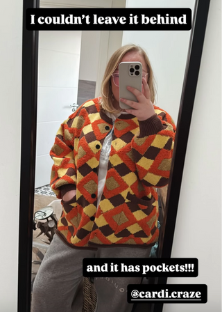 Person wearing a colorful patterned sweater taking a mirror selfie.